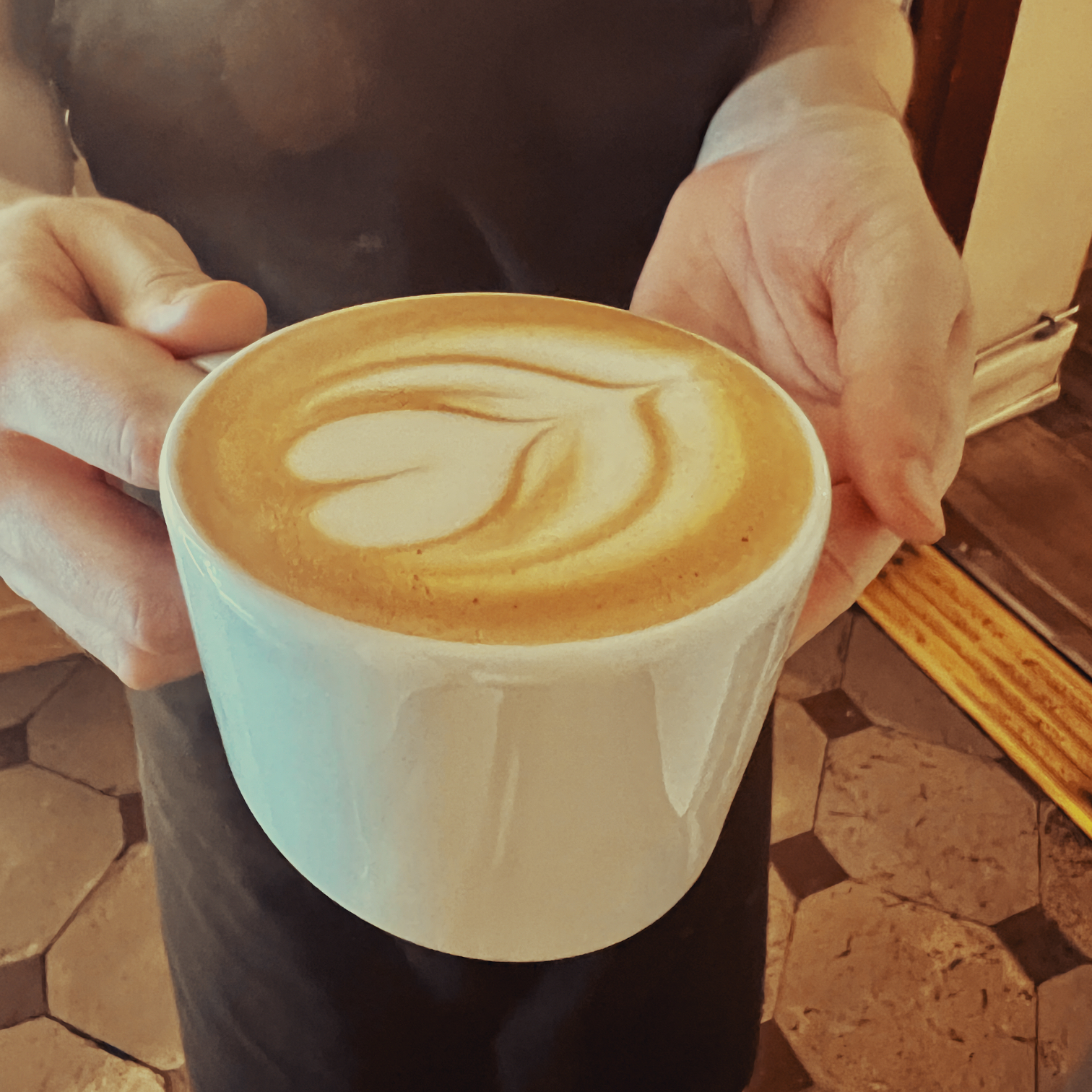 Barista holding a cup of caffé latte
